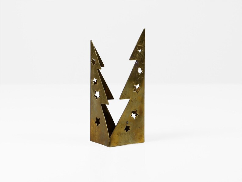 May include: A gold metal Christmas tree candle holder with a star cut-out design.