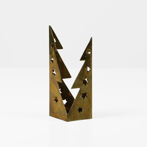 May include: A gold metal Christmas tree candle holder with a cut-out design of stars.