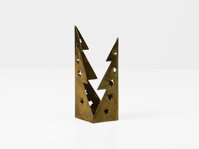 May include: A gold metal Christmas tree candle holder with a cut-out design of stars.