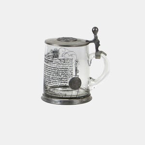 Op de afbeelding: Een heldere glazen bierpul met een metalen deksel en handvat. De pul heeft geëtste tekst en decoratieve elementen. Het deksel is scharnierend en heeft een kleine bal bovenop.
