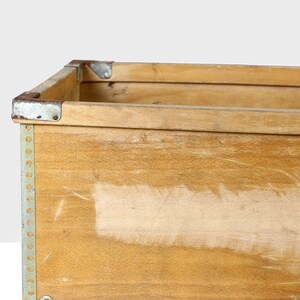 May include: A wooden storage box with metal corners and a light wood finish. The box has a worn, vintage look.