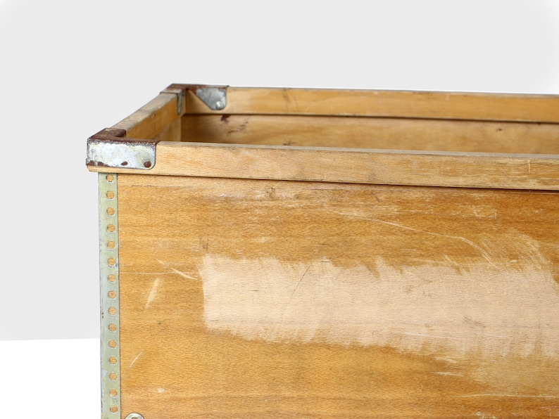 May include: A wooden storage box with metal corners and a light wood finish. The box has a worn, vintage look.
