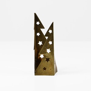 May include: A brass candle holder shaped like two overlapping triangles with cut-out star designs.