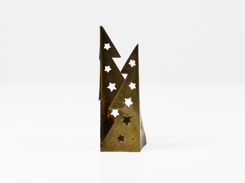 May include: A brass candle holder shaped like two overlapping triangles with cut-out star designs.