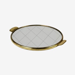 Op de afbeelding: Een ronde messing dienblad met een gespiegelde oppervlak en twee kleine handvatten. De spiegel heeft een rasterpatroon.