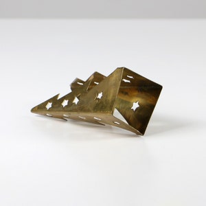 May include: A gold-coloured metal Christmas tree ornament with a star-shaped cutout design.