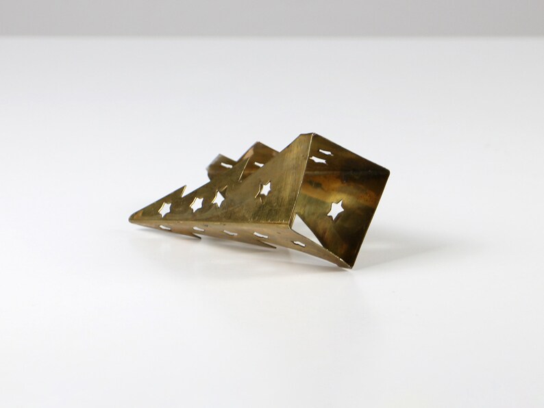 May include: A gold-coloured metal Christmas tree ornament with a star-shaped cutout design.