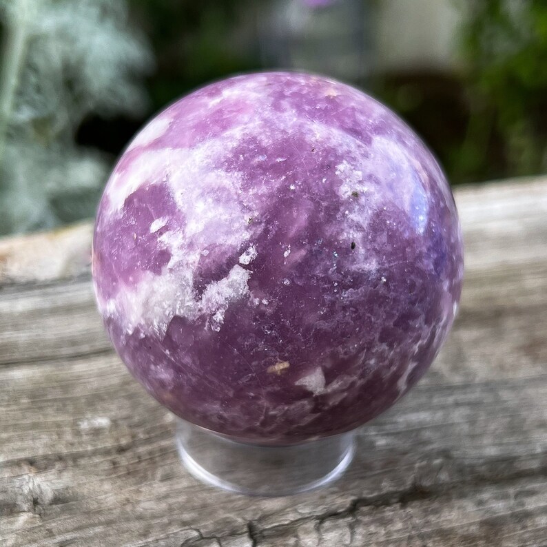 May include: A purple and white Lepidolite sphere on a clear stand. The sphere is polished and has a swirling pattern.