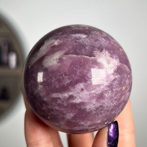 May include: A polished purple amethyst sphere with white swirls and a smooth, shiny surface.