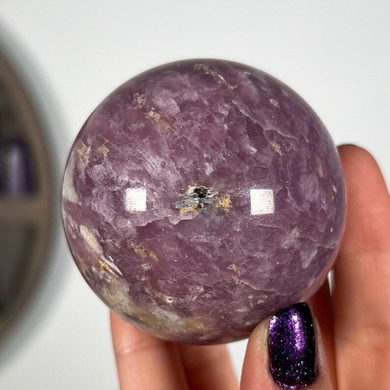 May include: A large, purple amethyst sphere with a swirling pattern and a small black inclusion in the center.