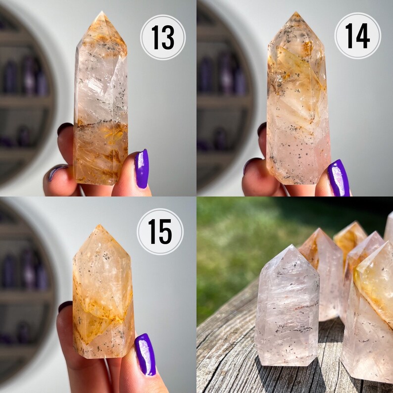 May include: Four clear quartz crystal points with inclusions of golden rutile and a hint of pink. The crystals are displayed on a wooden surface and in hands.