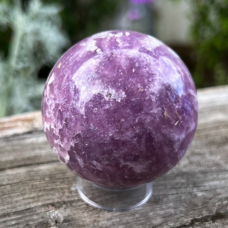 May include: A purple and white Lepidolite sphere on a clear stand. The sphere has a swirling pattern of white and purple.