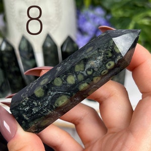 Pode incluir: Uma ponta de cristal verde escuro e preto com um padr&atilde;o &uacute;nico de manchas brancas e verdes. O cristal &eacute; polido e tem um acabamento liso e brilhante.