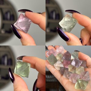 May include: A collection of fluorite crystals in various shades of green, pink, and purple. The crystals are octahedral in shape and have a glassy lustre.