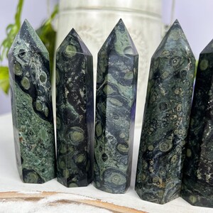 Pode incluir: Cinco pontas de pedra serpentina verde e preta, tamb&eacute;m conhecidas como serpentina verde, est&atilde;o dispostas em fila. As pontas s&atilde;o polidas e t&ecirc;m um acabamento liso e brilhante. As pedras s&atilde;o de cor verde escura com redemoinhos e padr&otilde;es pretos e brancos.