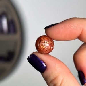 May include: A round, metallic, copper-coloured bead with a glittery, iridescent finish.