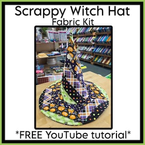 May include: A Scrappy Witch Hat Fabric Kit featuring a conical hat constructed from various fabric strips in black, orange, purple, and lime green. The patterns include pumpkins, plaid, and polka dots. The text reads Scrappy Witch Hat Fabric Kit.