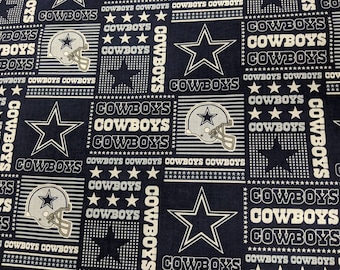 May include: A navy blue fabric with a repeating pattern of white stars, the Dallas Cowboys logo, and the word "COWBOYS" in white text.