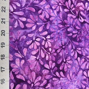 May include: A fabric with a floral pattern in shades of purple and pink. The design features stylized leaf-like shapes against a mottled background. A ruler with inch measurements is visible on the left side.