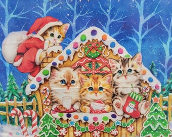 May include: Four adorable kittens dressed in festive attire are gathered around a gingerbread house decorated with candy canes, stars, and a wreath. The house is set against a blue background with white snow and trees.
