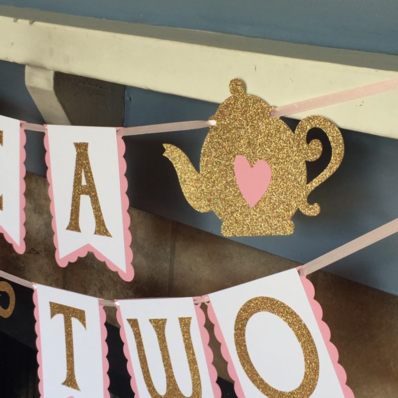 May include: A pink and gold glitter tea party banner with the words "Tea for Two" and a gold glitter teapot with a pink heart.
