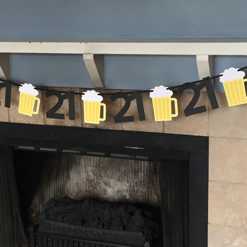 Pu&ograve; includere: Striscione di compleanno nero e giallo con boccali di birra per il 21&deg; compleanno. Lo striscione &egrave; appeso sopra un camino.