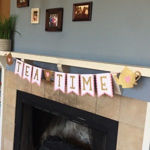 May include: A pink and gold tea party banner with the words "TEA TIME" and a teapot and teacup design.