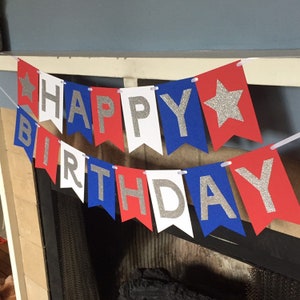Puede incluir: Bandera roja, blanca y azul con letras de purpurina plateada que dice "Happy Birthday".