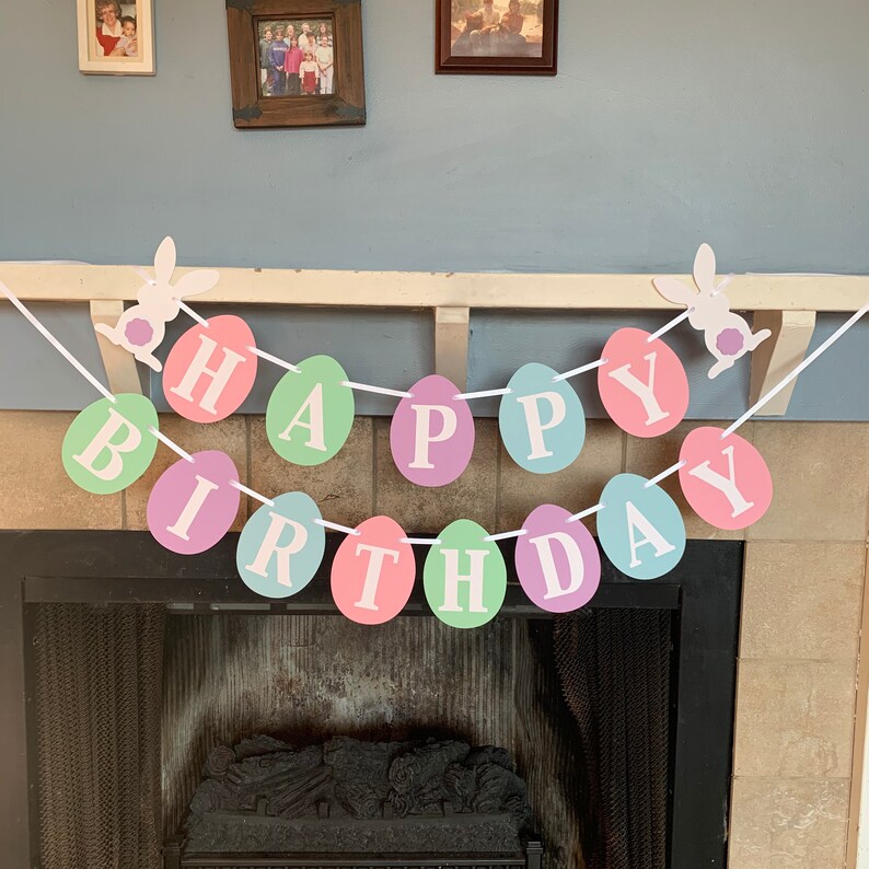 May include: A pastel-colored Happy Birthday banner with bunny rabbit cutouts. The banner is made of paper and has the words "Happy Birthday" spelled out in individual circles.