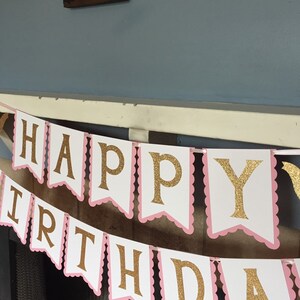 May include: A white and pink banner with gold glitter letters that reads "Happy Birthday".