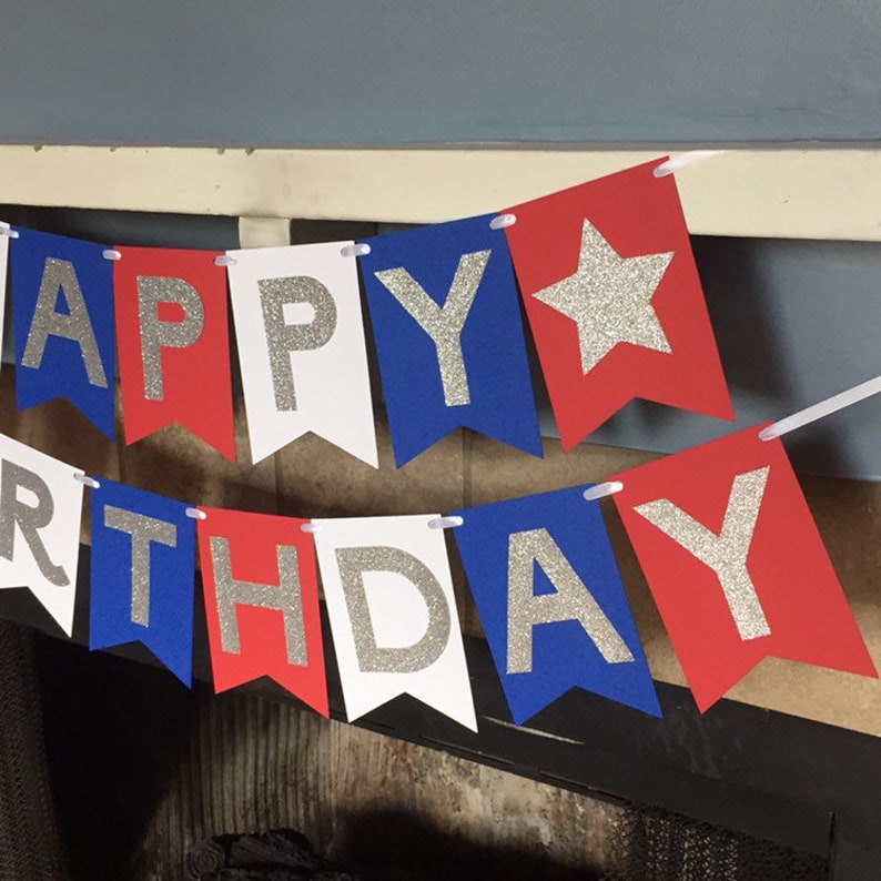 Puede incluir: Bandera de Feliz Cumplea&ntilde;os con banderines rojos, blancos y azules. Cada bander&iacute;n tiene una letra o una estrella de purpurina plateada.