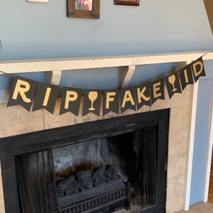 May include: Black and gold banner with the text "RIP FAKE ID" and a wine glass icon.