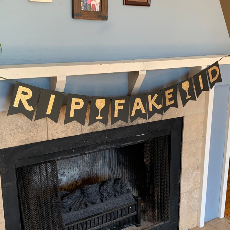 May include: Black and gold banner with the text "RIP FAKE ID" and a wine glass icon.