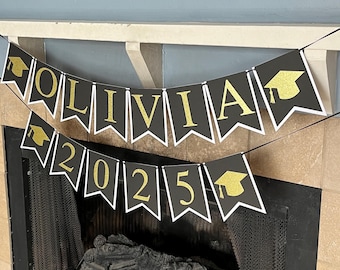 May include: Black and white graduation banner with gold glitter letters spelling "OLIVIA 2025". Each letter is on a separate pennant with a gold graduation cap on each end.
