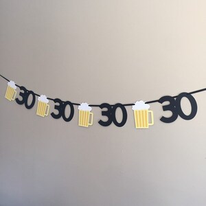 May include: Black and yellow paper banner with the number 30 repeated and beer mug cutouts.