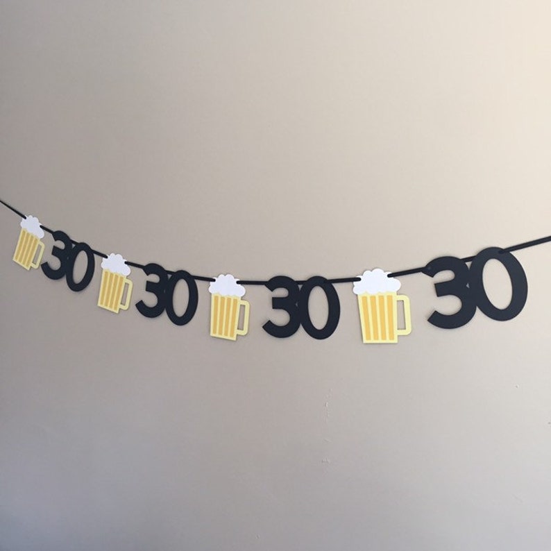 May include: Black and yellow paper banner with the number 30 repeated and beer mug cutouts.