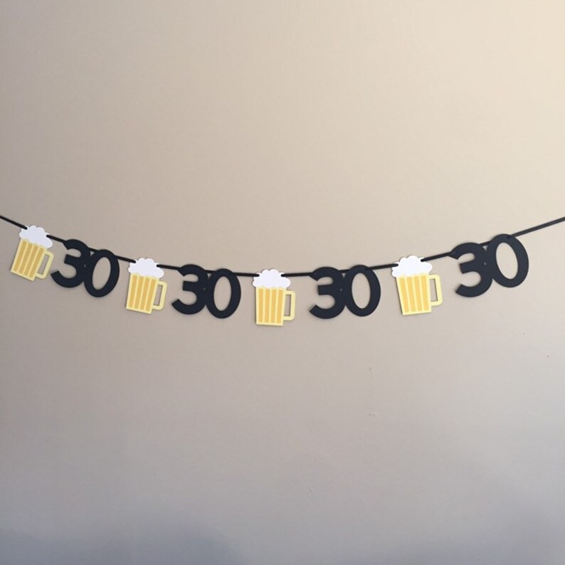 May include: Black and yellow paper banner with the number 30 repeated and beer mug cutouts.