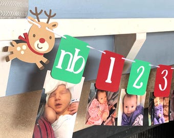 Könnte beinhalten: Ein Baby-Fotobanner mit einer Rentierdekoration. Das Banner hat grüne und rote Wimpel mit den Buchstaben "nb" und den Zahlen 1, 2 und 3. Fotos eines Babys sind an dem Banner befestigt.