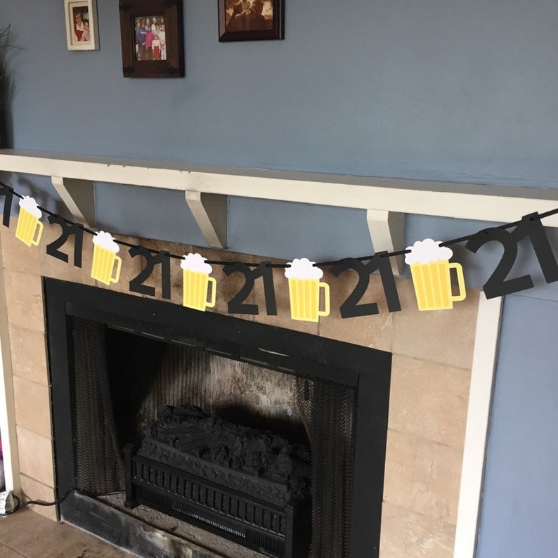 Pu&ograve; includere: Striscione di compleanno nero e giallo con boccali di birra per il 21&deg; compleanno. Lo striscione &egrave; appeso sopra un camino.
