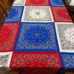 May include: A red, white, and blue bandana patterned tablecloth. The tablecloth is made of fabric and has a paisley design.