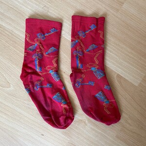 Puede incluir: Un par de calcetines rojos con un patrón de cadenas doradas y llaves azules.