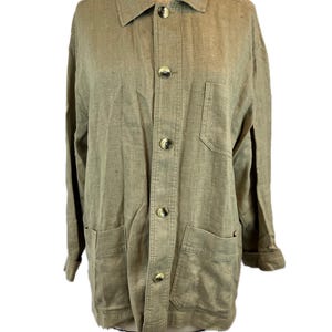 May include: A tan linen jacket with a collared neckline, button-up front, and two front pockets. The jacket has long sleeves and a relaxed fit. The buttons are a darker shade of brown. The jacket is displayed on a mannequin.
