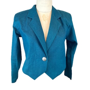 May include: Teal blazer with a single silver button closure. The blazer has a classic notched lapel and long sleeves. The jacket is displayed on a mannequin.