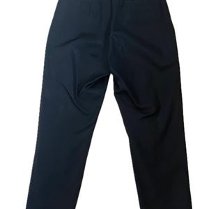 May include: A pair of navy blue trousers, viewed from the back. The pants have a straight leg design and feature two back pockets. The fabric appears smooth and wrinkle-free, suggesting a tailored fit. The trousers are suitable for various occasions.