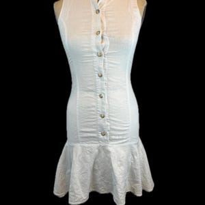 Vestido de verano sin mangas con botones y cintura baja, estilo años 80, de lino y algodón, color blanco crema, con tirantes finos, minifalda hasta la rodilla, bajo con volantes, corpiño ajustado y cuello mandarín.