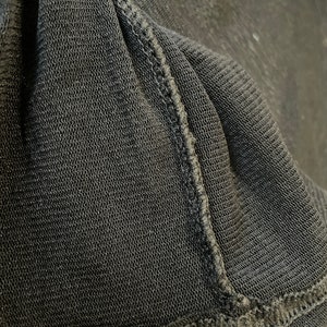 May include: Close-up of black fabric with a textured weave and a stitched seam.