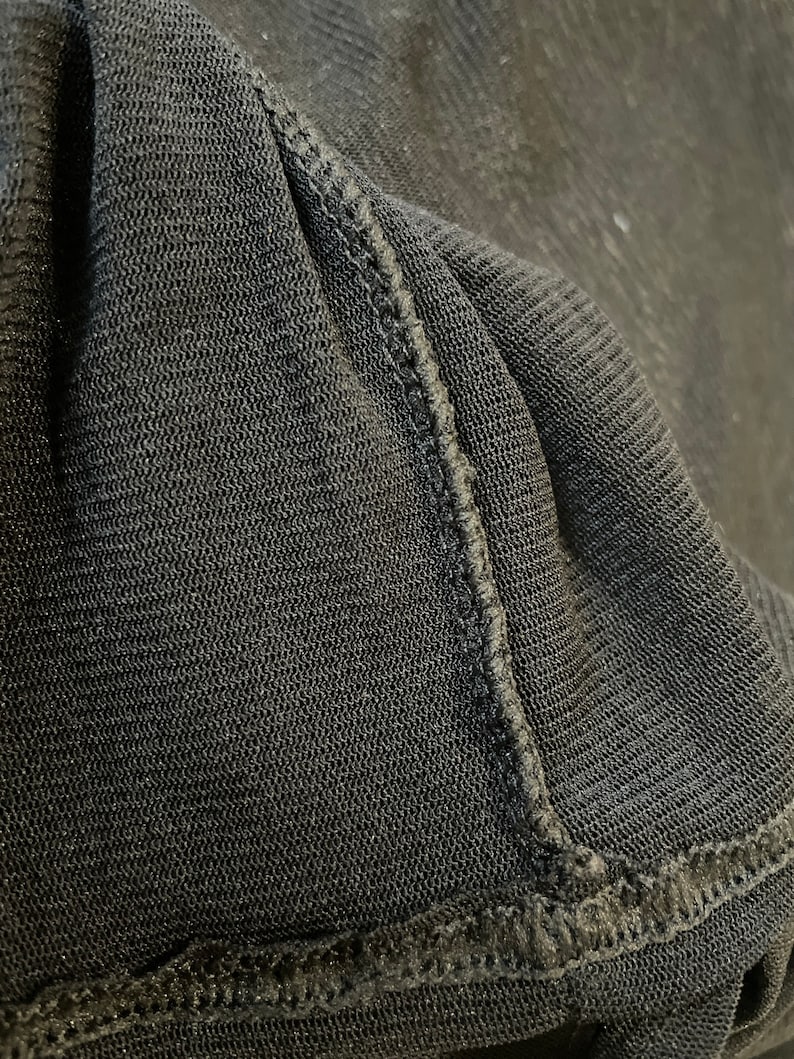 May include: Close-up of black fabric with a textured weave and a stitched seam.