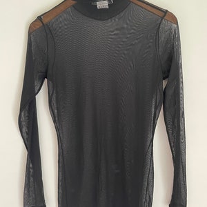 May include: Black sheer long-sleeved turtleneck top with a mock neck.