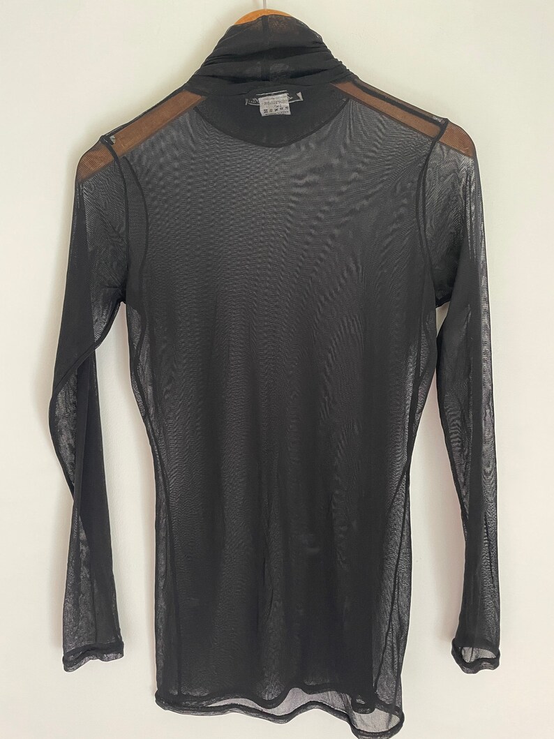 May include: Black sheer long-sleeved turtleneck top with a mock neck.