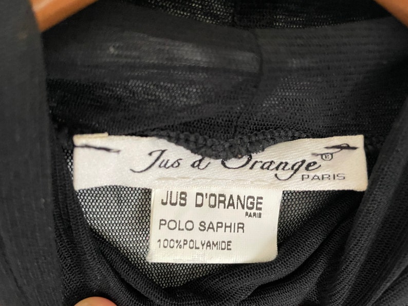 May include: Black sheer top with a white label that reads "Jus d'Orange Paris" and "Jus d'Orange Paris Polo Saphir 100% Polyamide".